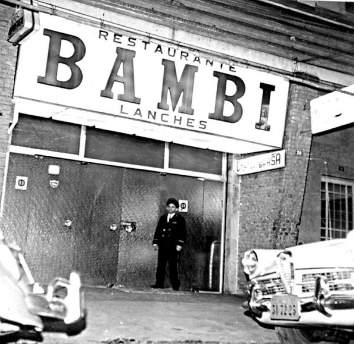 Fachada antiga do Restaurante Bambi Lanches, com letreiro grande e um funcionário uniformizado na porta